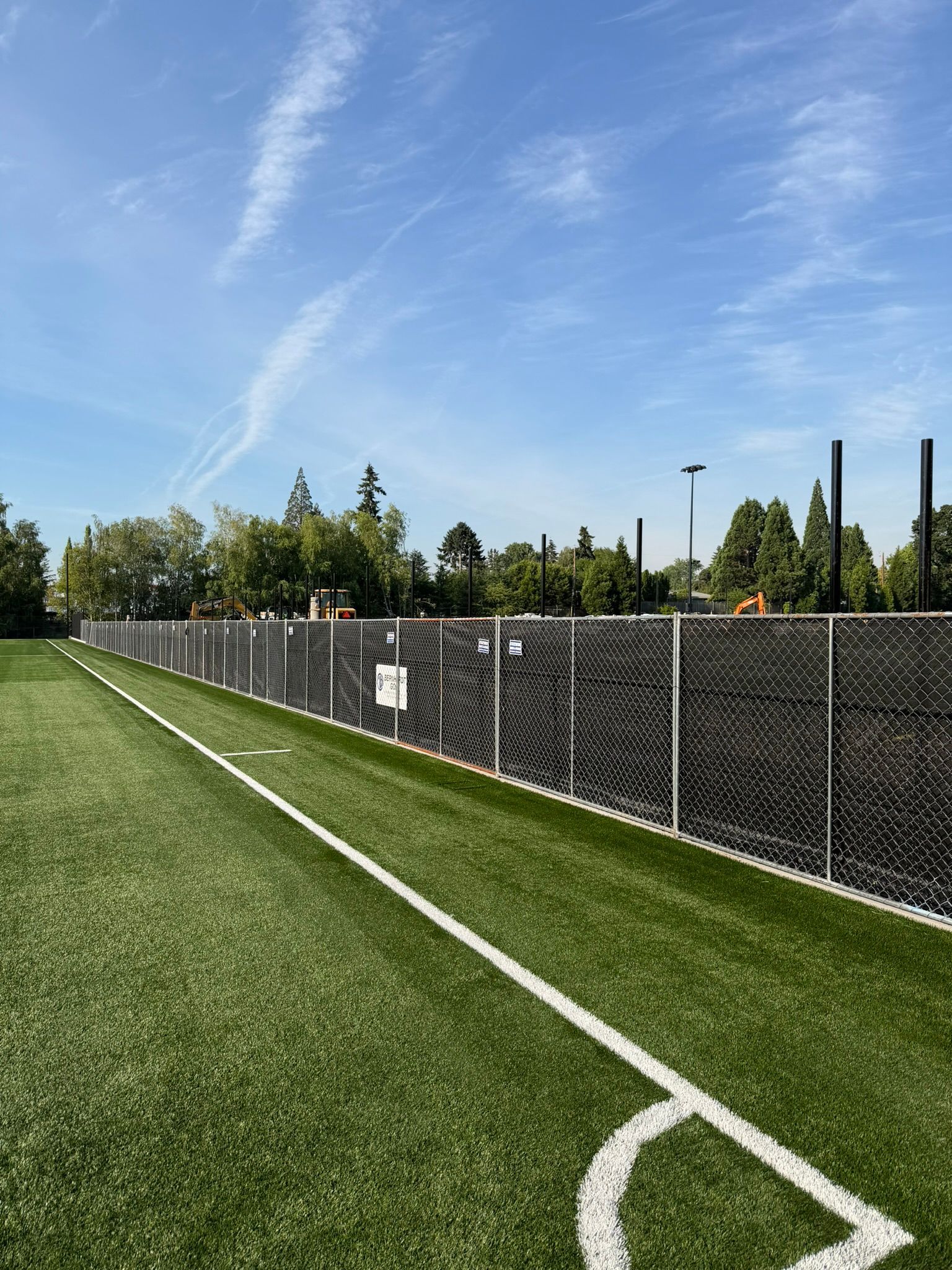 Green chain-link fence with metal posts in a grassy outdoor area