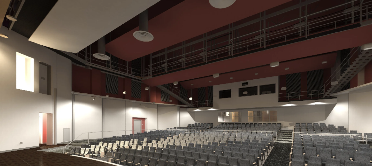An auditorium with rows of seating, stage at the far end, and red ceiling.