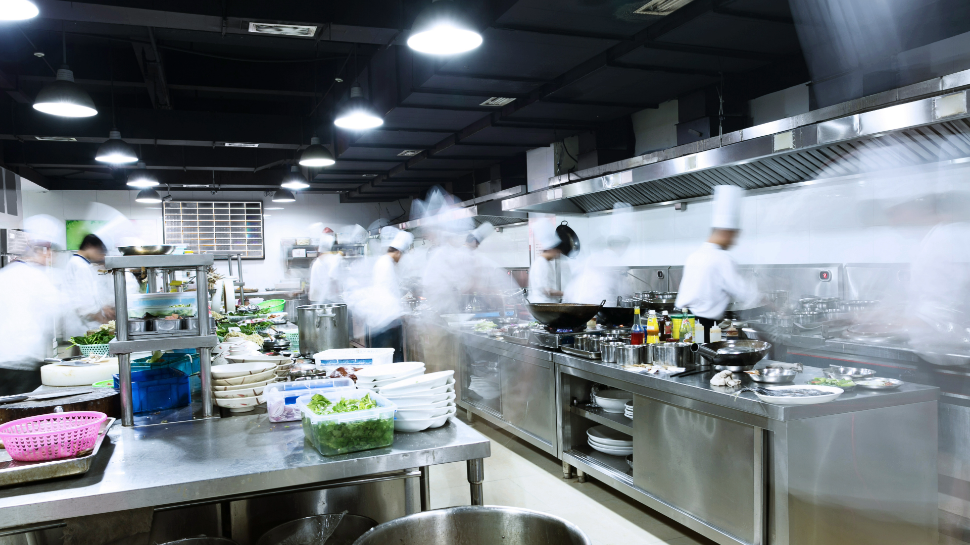 A picture of a commercial kitchen with staff working so fast that the photographer made the staff blurry with shadows and what not to express motion 