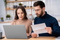 Two coworkers reviewing a laptop and paper document at a desk in an office