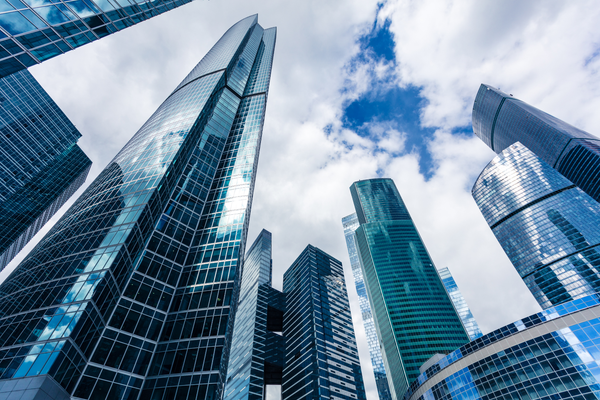 Looking up at a group of skyscrapers against a cloudy sky.