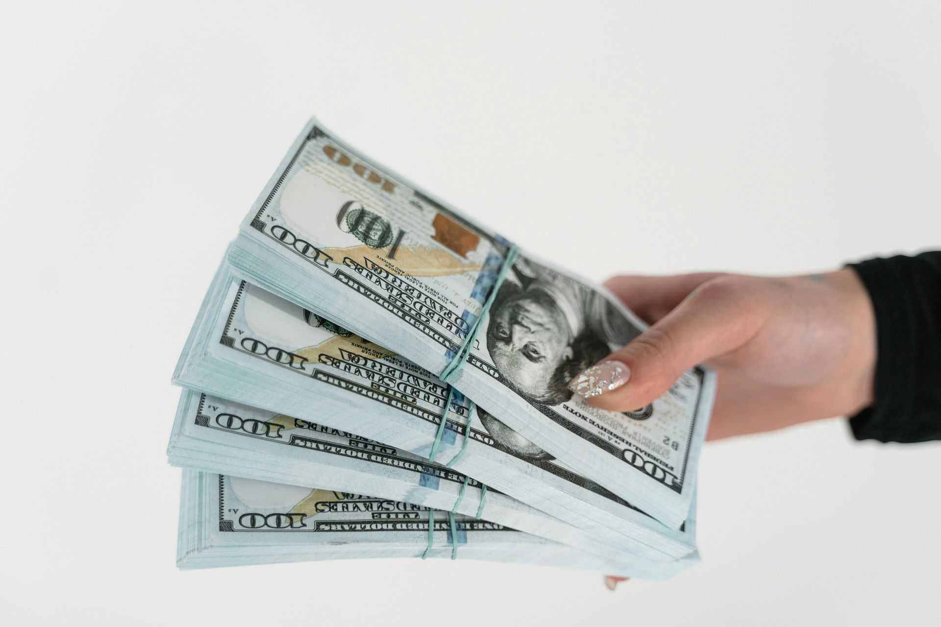 A person is holding a stack of money in their hand.