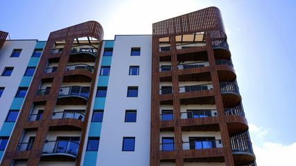 A tall building with balconies and a blue sky in the background
