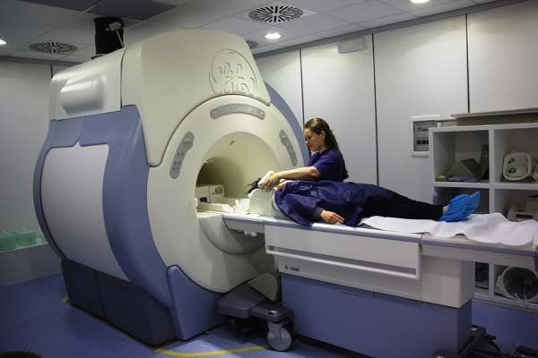 Una donna è sdraiata su un letto davanti a una macchina per la risonanza magnetica.