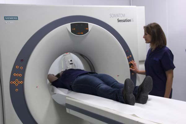 Una donna è sdraiata su un letto davanti a una macchina per la TAC.