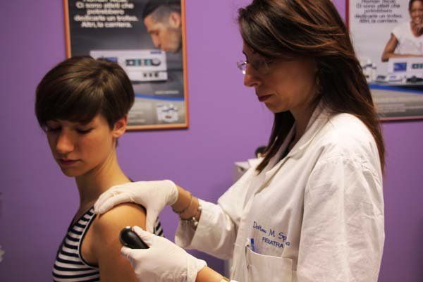 Una donna in camice bianco sta esaminando il braccio di un'altra donna