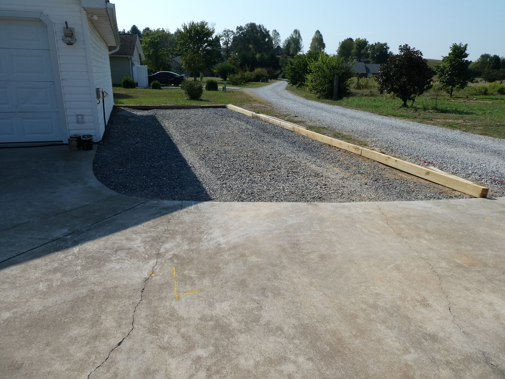 John Deere bulldozer grading a gravel path winding through a wooded area.