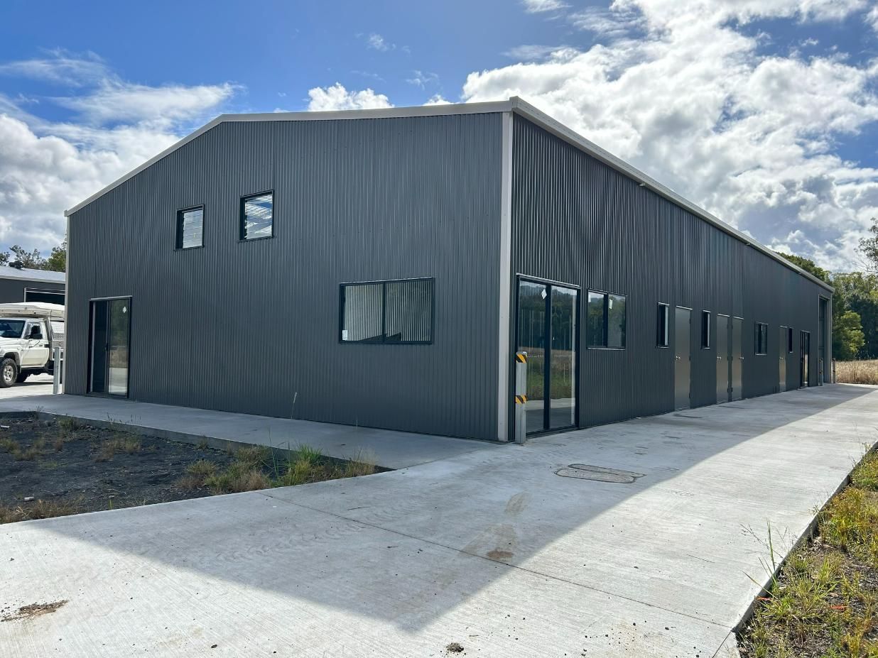 A Large Building With a Lot of Windows and a Truck Parked in Front of It — Mbah Metal Roofing in South Pottsville, NSW