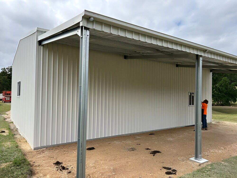 A Man Is Standing In Front Of A White Metal Building — Mbah Metal Roofing In Murwillumbah, NSW