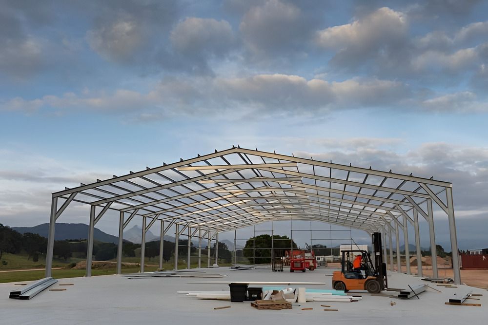 A Large Metal Structure Is Being Built With A Forklift In The Background — Mbah Metal Roofing In Murwillumbah, NSW