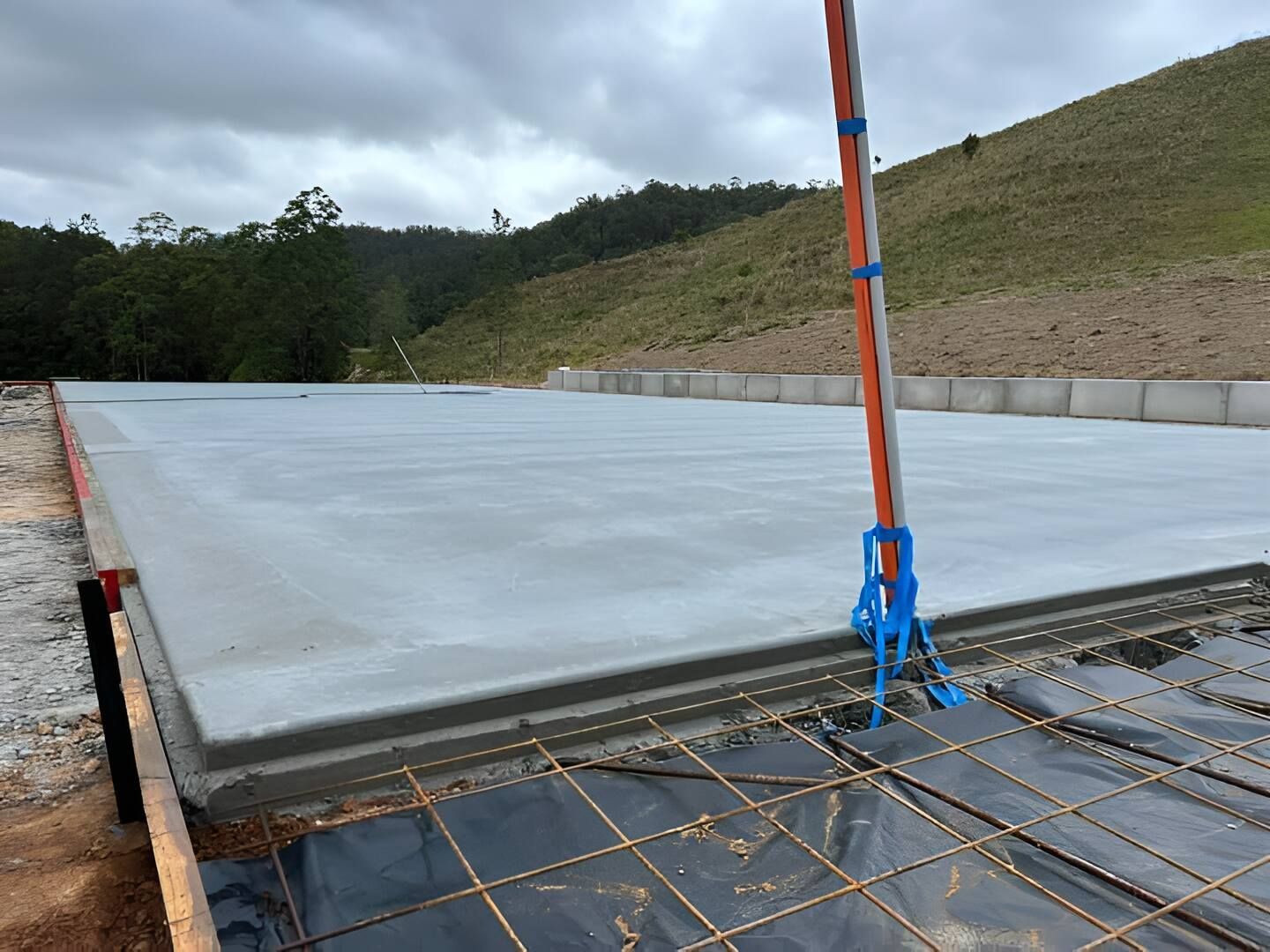 A Large Concrete Slab Is Being Built On A Hillside — Mbah Metal Roofing In Murwillumbah, NSW