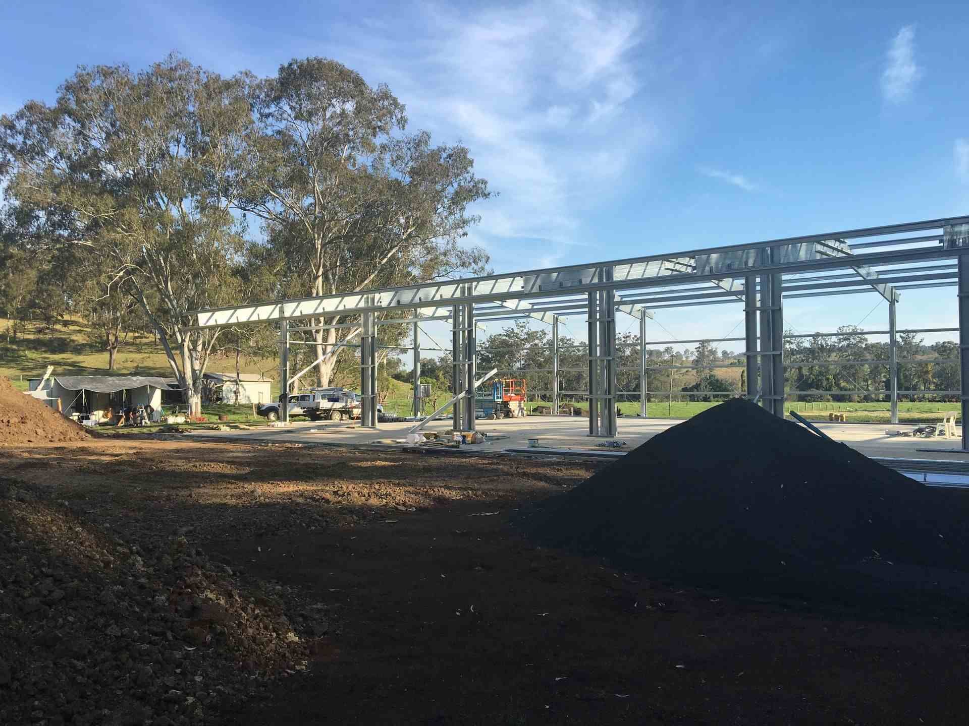 A Large Pile Of Dirt Is Sitting In Front Of A Building Under Construction — Mbah Metal Roofing In Murwillumbah, NSW
