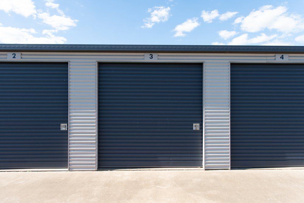 A Row Of Storage Units With Roller Doors On A Sunny Day — Mbah Metal Roofing In Murwillumbah, NSW
