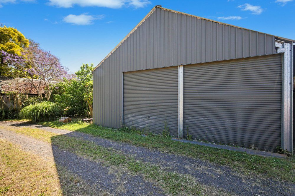 A Garage With Two Garage Doors Is Sitting Next To A Dirt Road — Mbah Metal Roofing In Murwillumbah, NSW