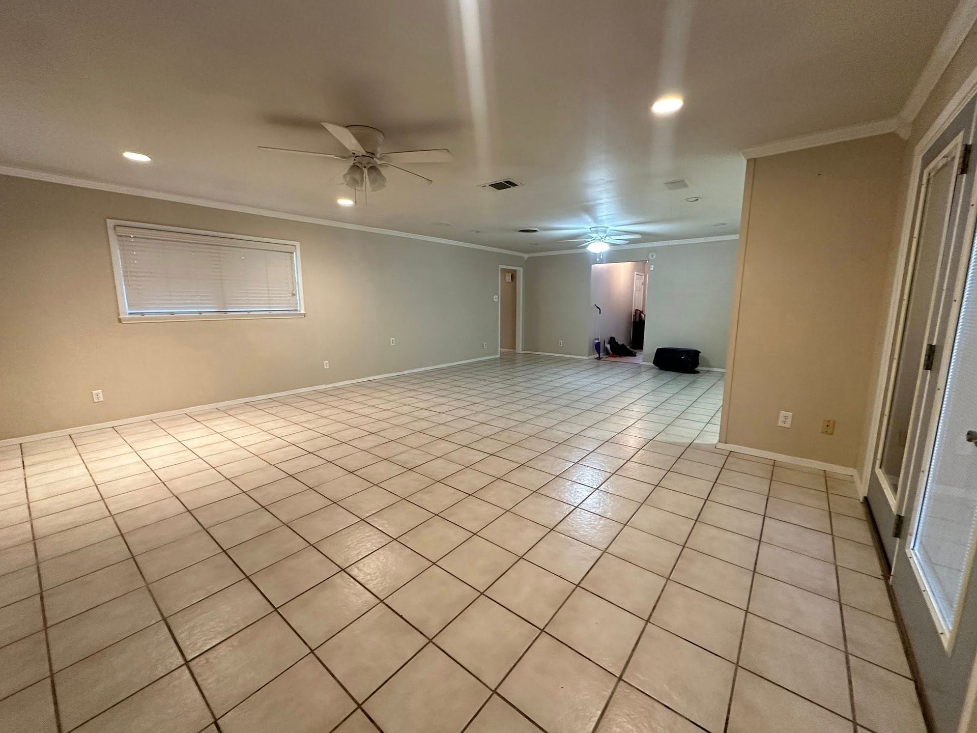 Empty room with tiled floor, white walls, and a ceiling fan.
