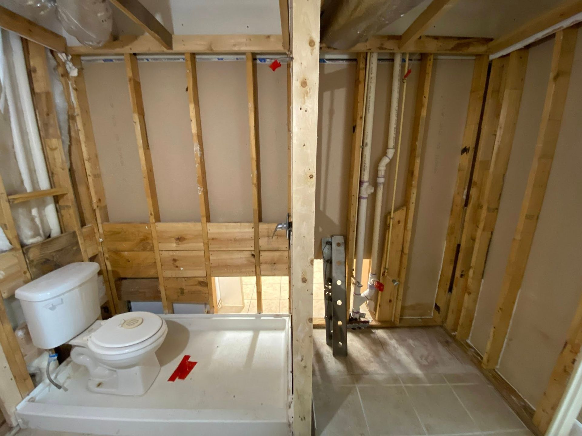 Bathroom renovation: Toilet, shower base, exposed plumbing and framing.