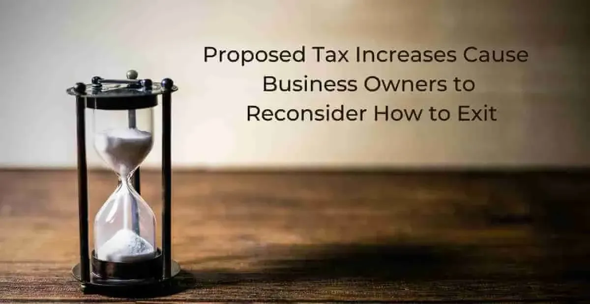 Hourglass on a wooden surface with text about tax increases and business owners reconsidering their exit strategies.