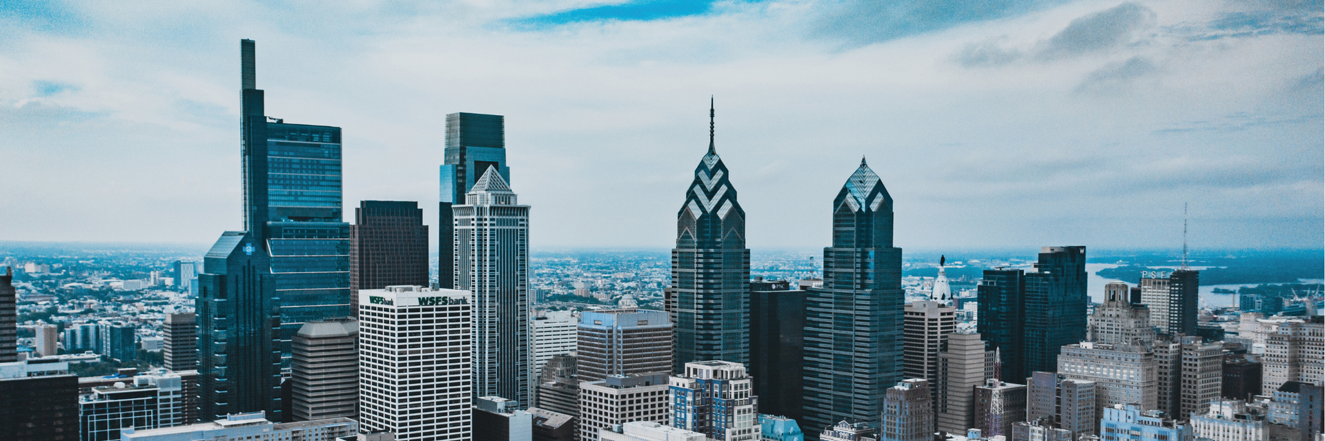 City skyline with tall, modern buildings under a cloudy sky.