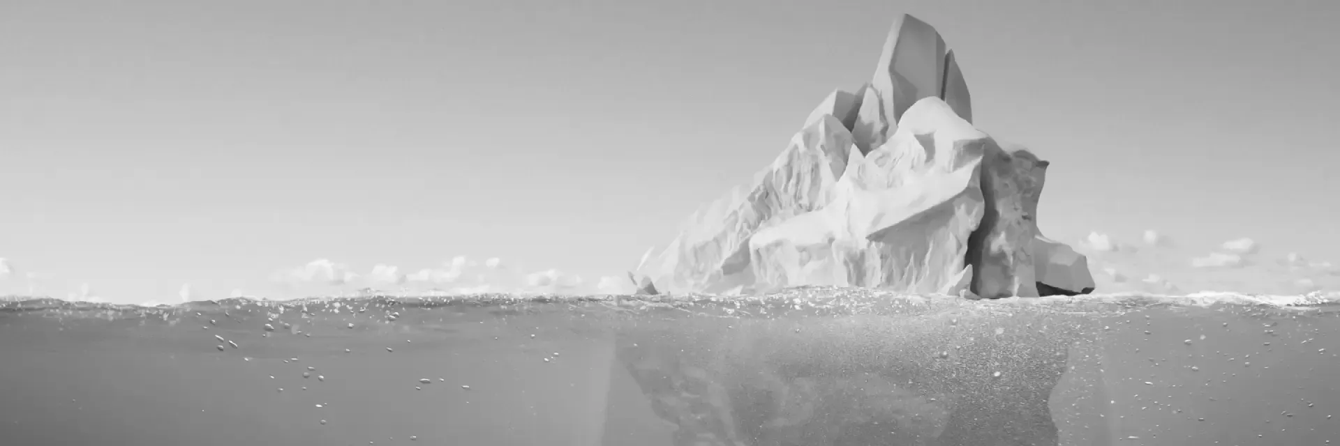 An iceberg floats in the water with a reflection. Black and white photo.