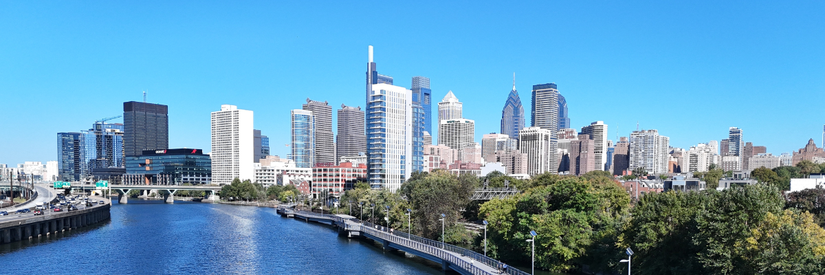 City skyline with modern high-rises beside a blue river under a clear sky