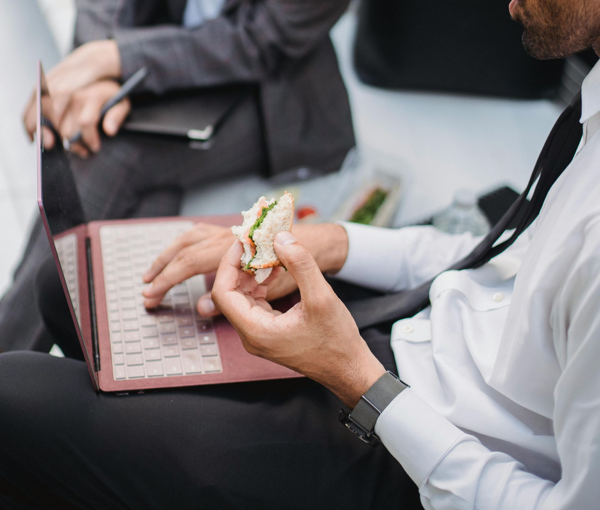 Group of people smiling, posing outdoors near a brick building.