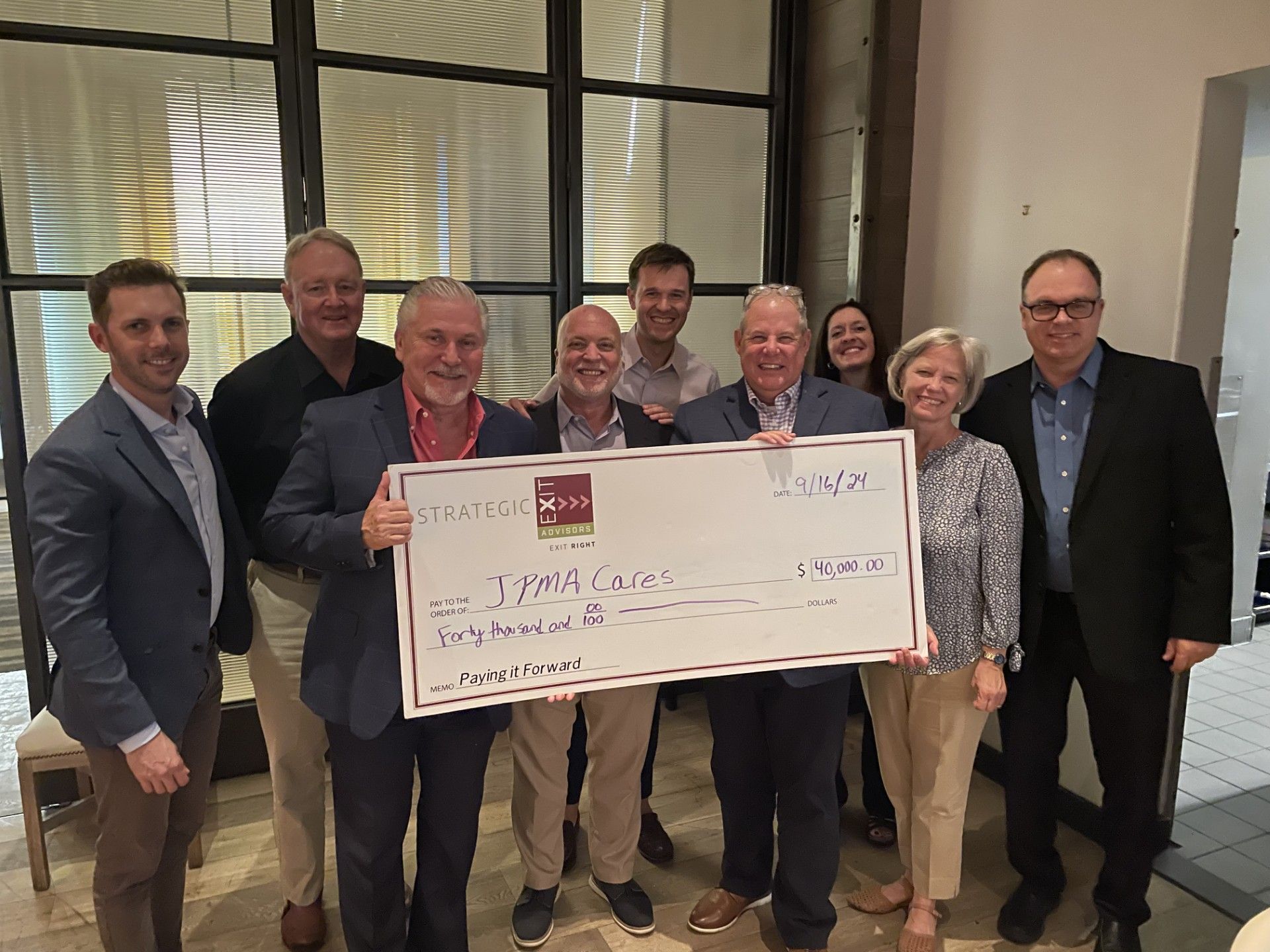 Group holds oversized check for Dolly Parton's Imagination Library. Inside a building.