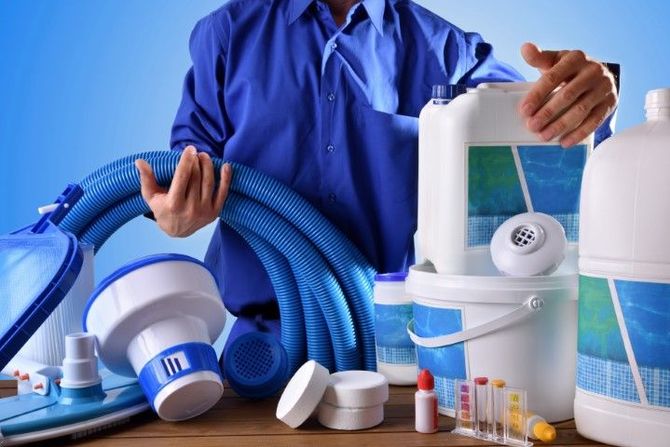 Person in blue shirt holding cleaning supplies and equipment on a white background