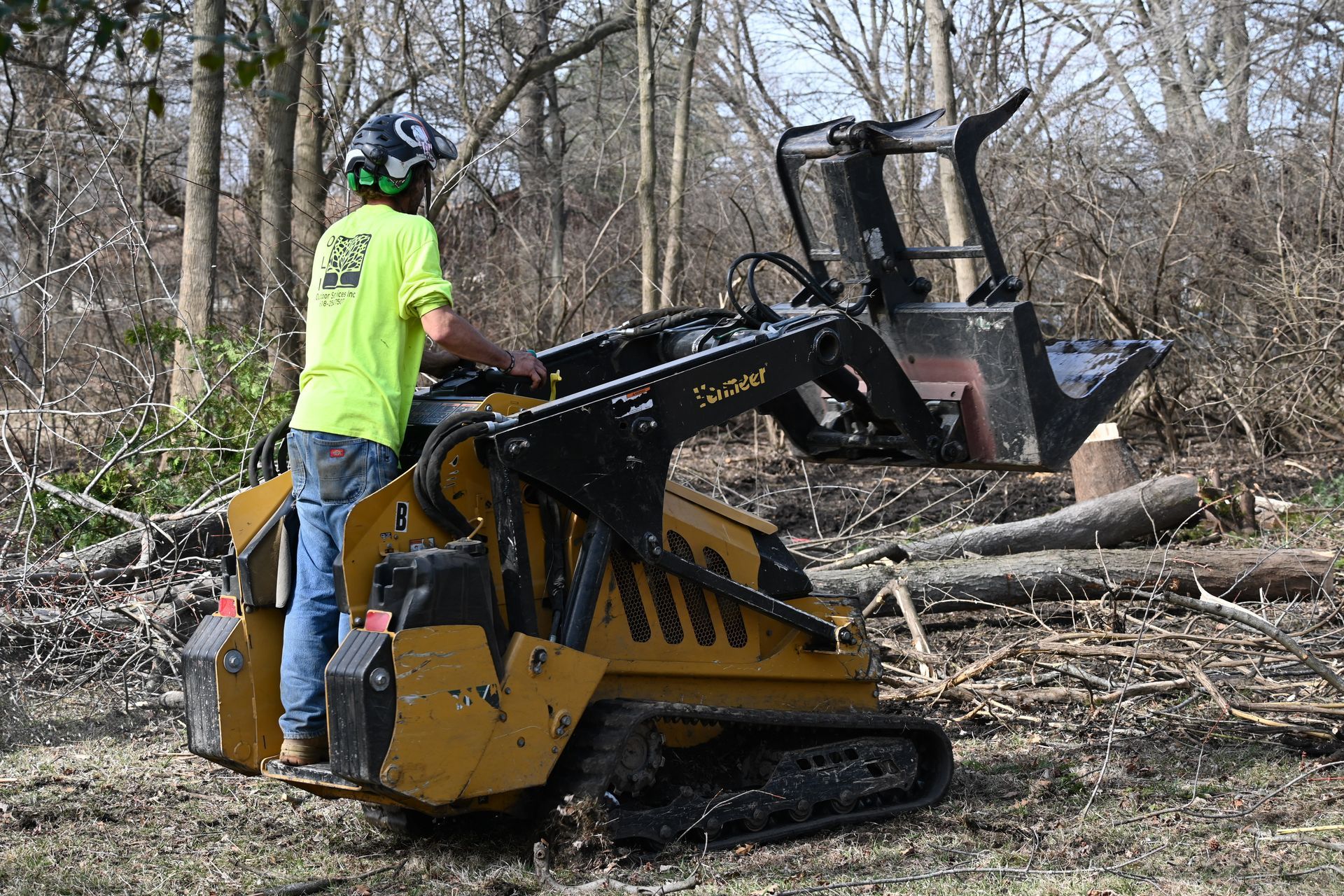 A man is operating a small tractor in a forest.