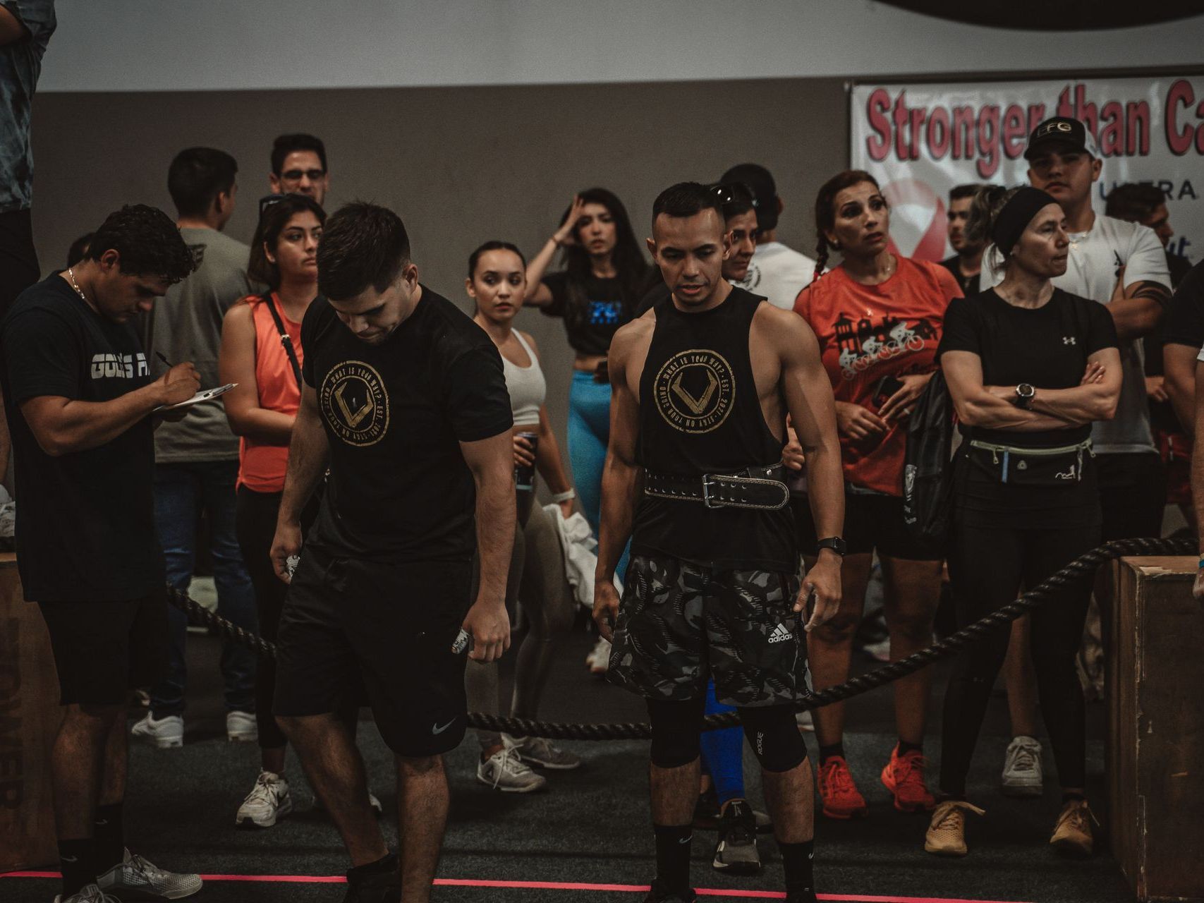 a group of people are standing around a barbell in a gym .