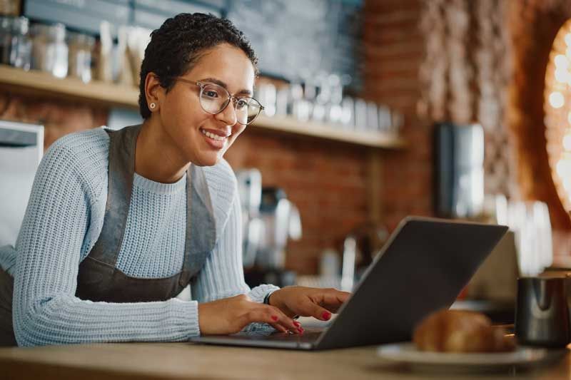 Woman restaurant owner happy at laptop