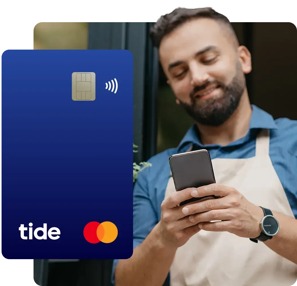 Happy millennial bearded european man in apron typing on phone at front door