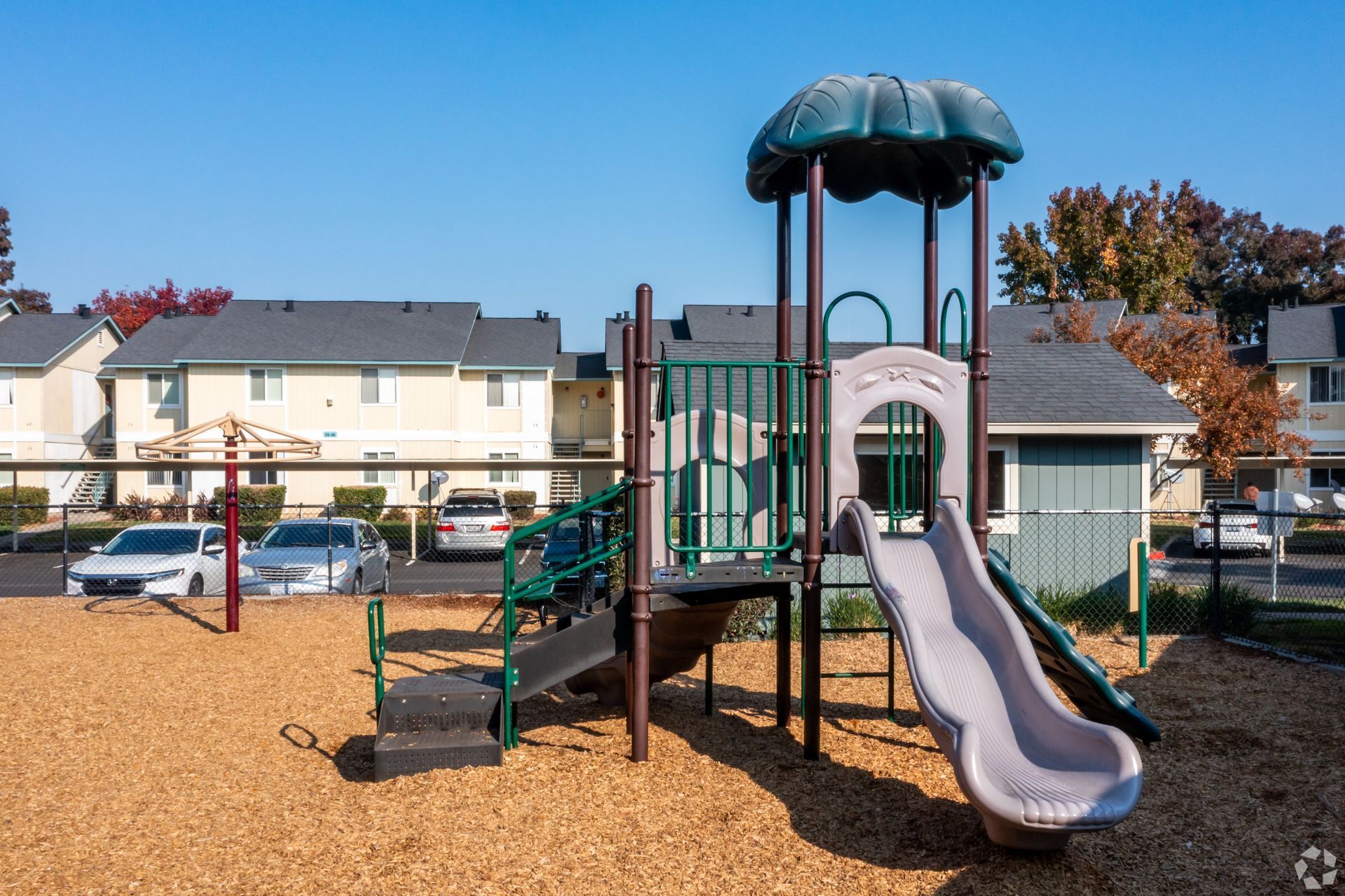 Playground with slide and climbing structure on wood chips in a residential area