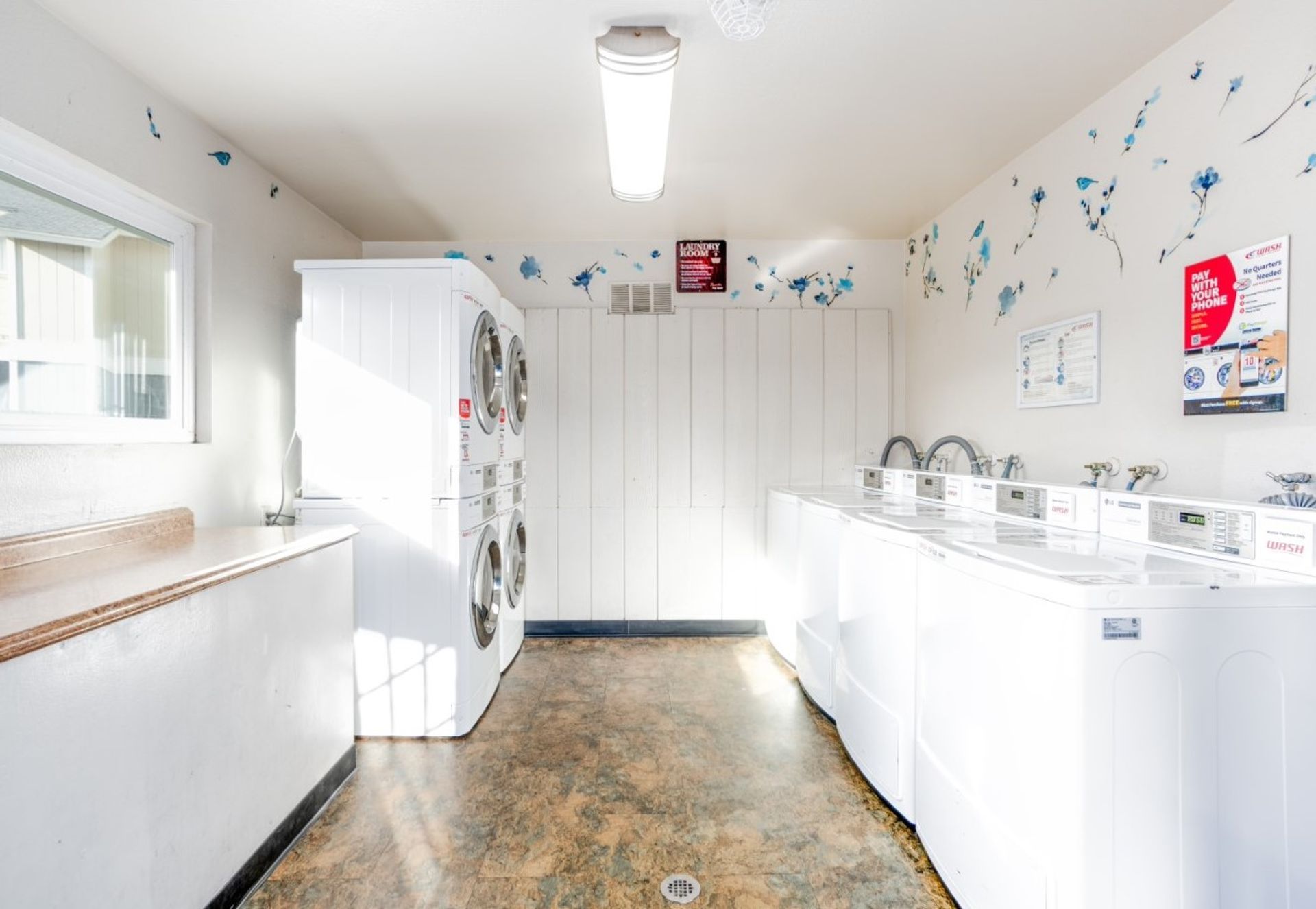 Bright laundry room with white cabinets, washer and dryer, and patterned floor tiles