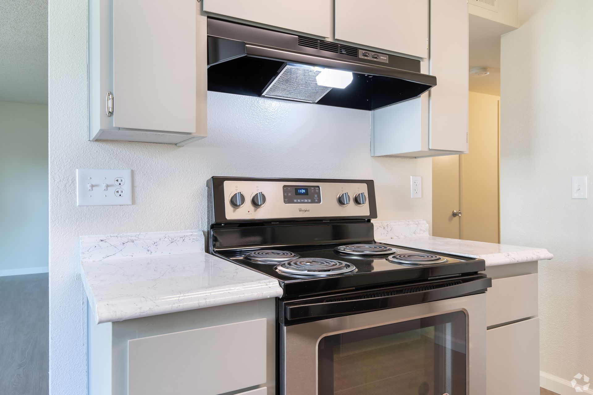 Modern kitchen with stainless steel stove, white cabinets, and light countertops