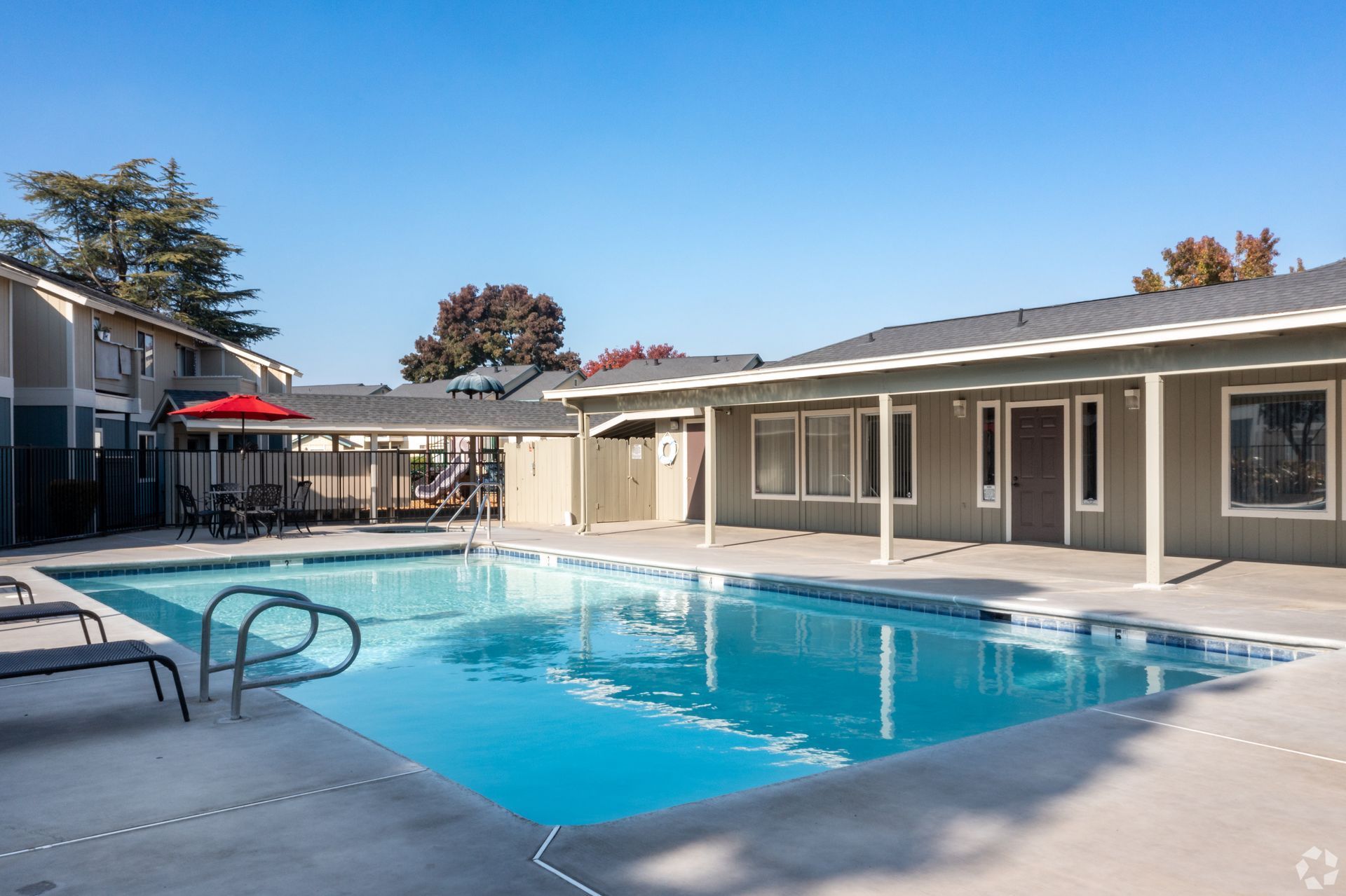 Apartment courtyard with a swimming pool and surrounding buildings under a clear blue sky