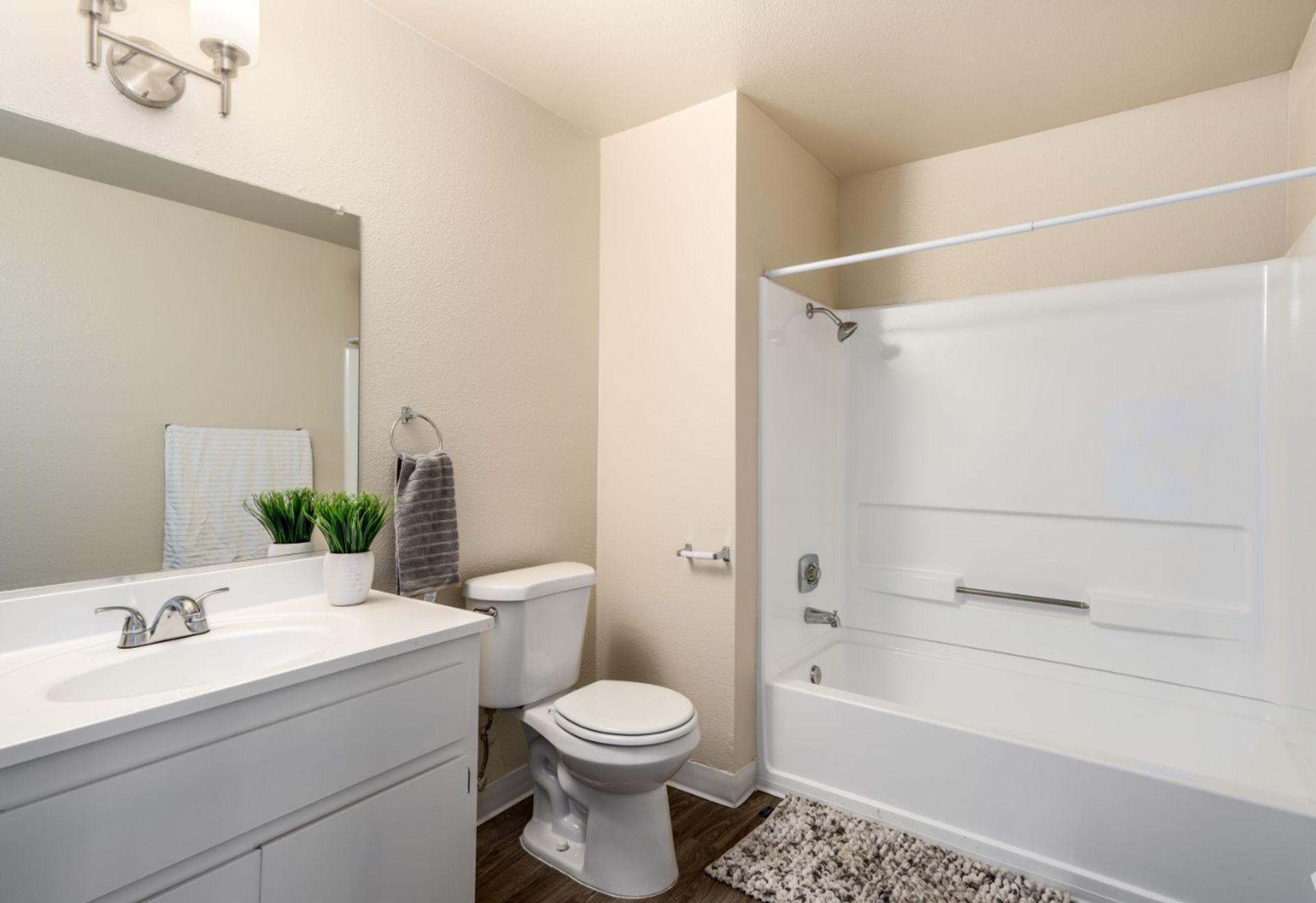 Bright bathroom with vanity, toilet, and white shower curtain over tub, seen from the sink area.