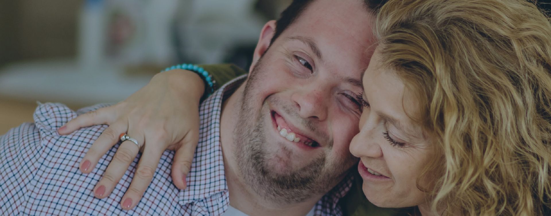 A woman is hugging a man with down syndrome and smiling.