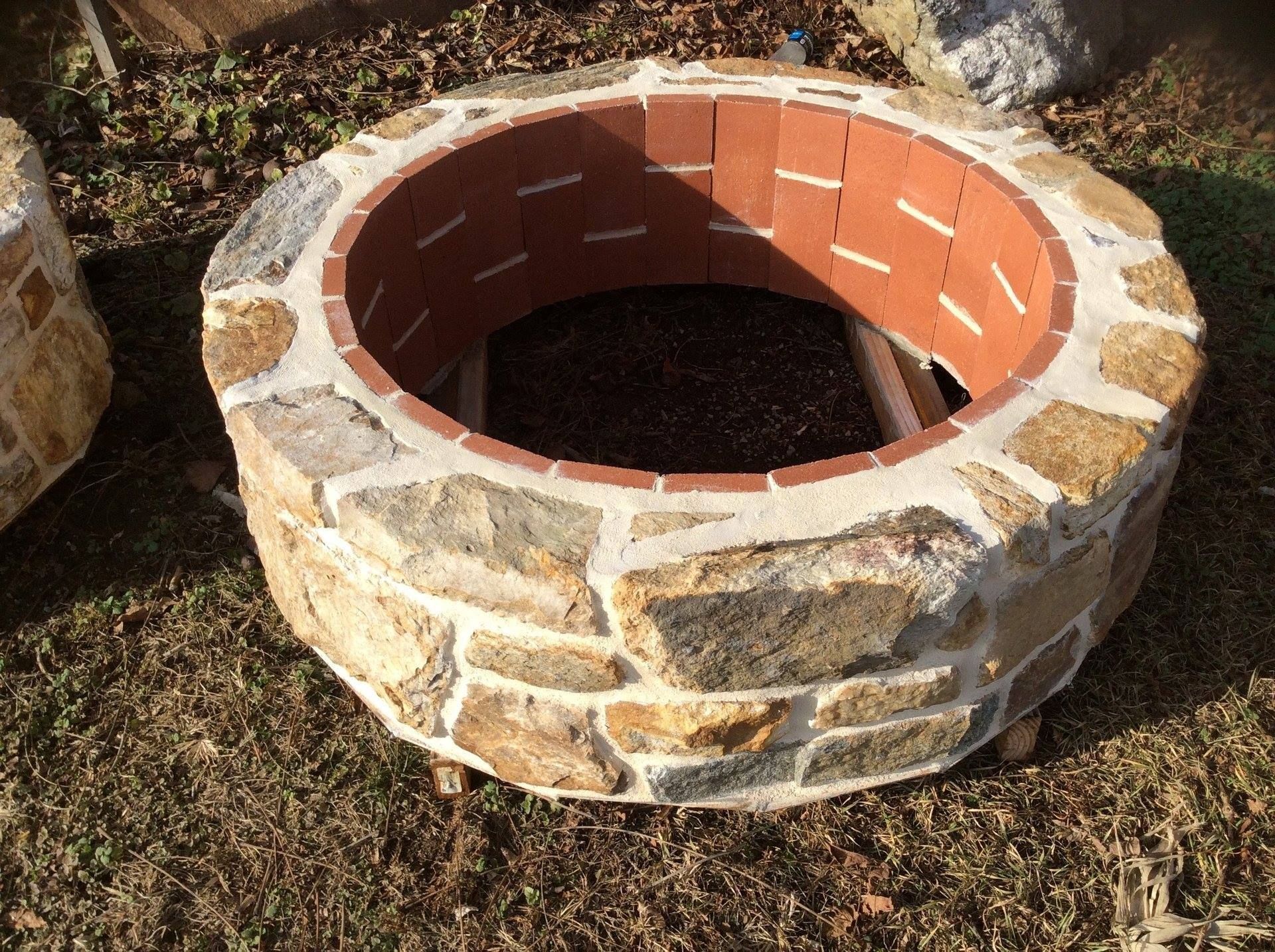 A stone fire pit is sitting in the grass.