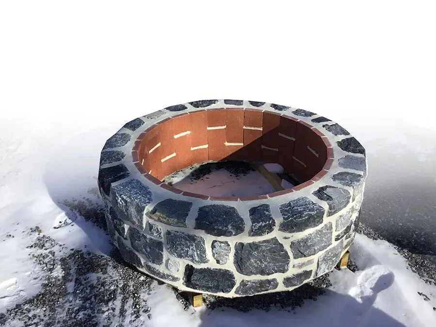 A stone fire pit is sitting in the snow