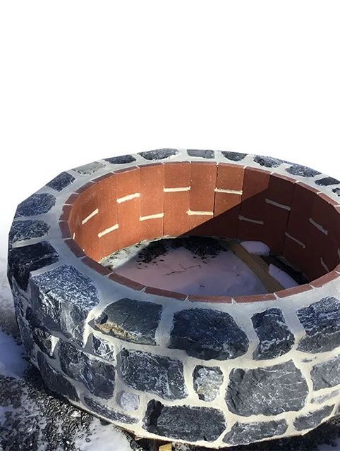 A fire pit made out of bricks is sitting in the snow