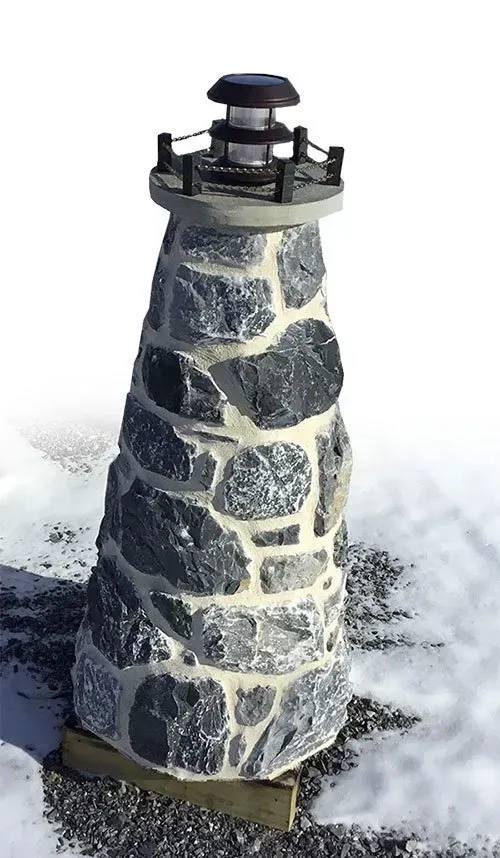 A small stone lighthouse is sitting in the snow.