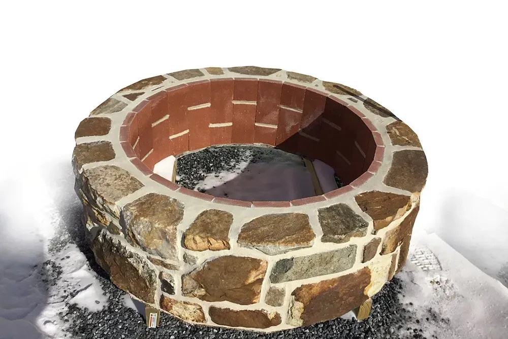 A stone fire pit is sitting in the snow.