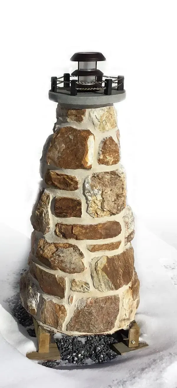 A small stone lighthouse is sitting in the snow.