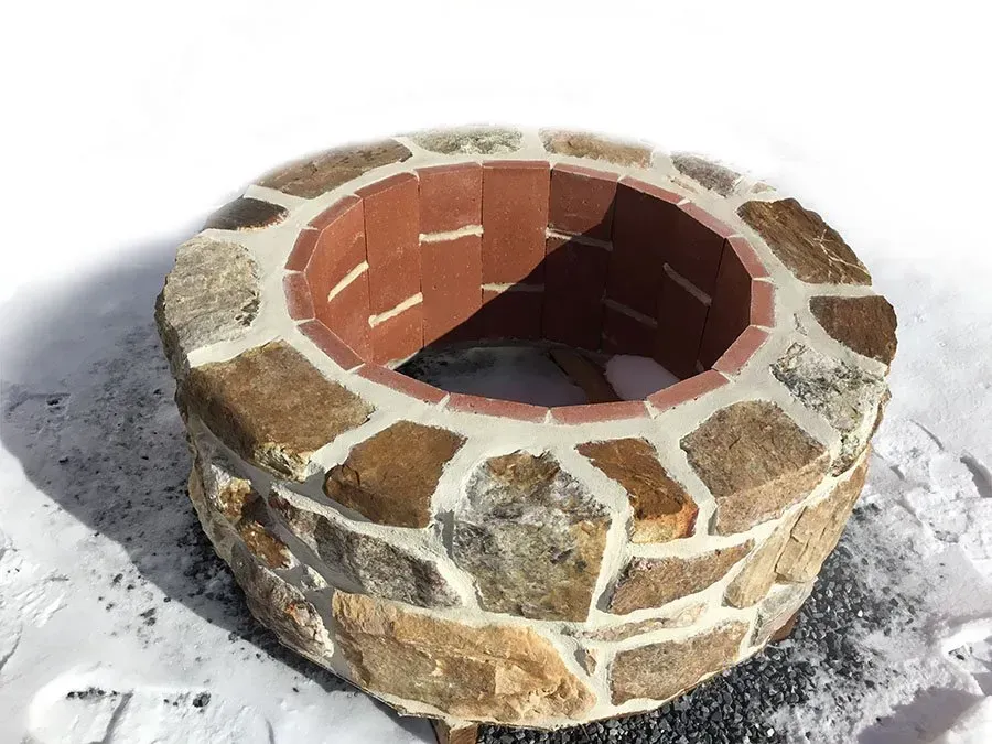 A stone fire pit is sitting in the snow