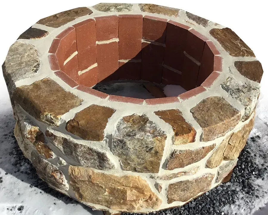 A stone fire pit is sitting in the snow