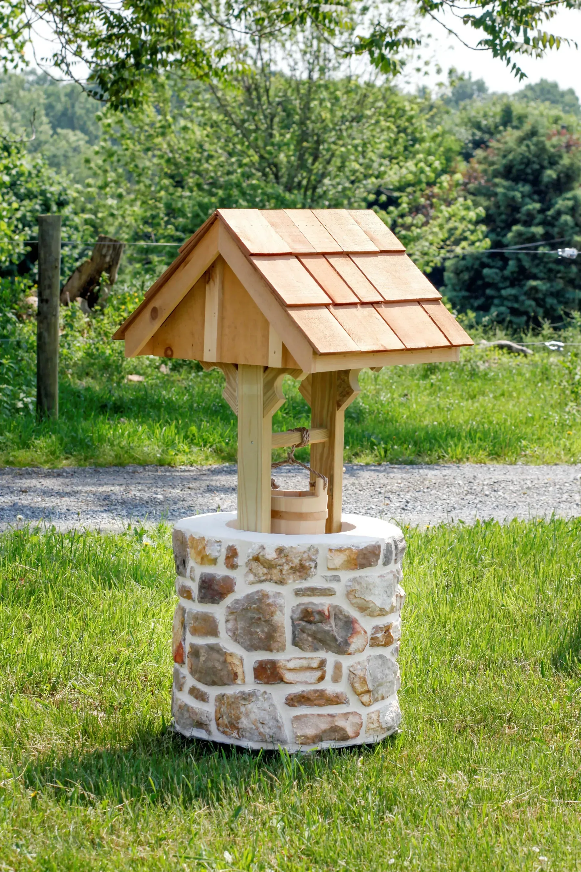 A wooden wishing well is sitting on top of a stone base.
