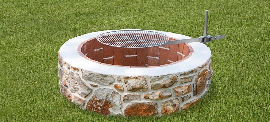 A fire pit is sitting in the middle of a lush green field.