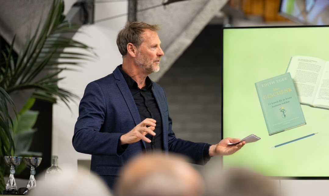 Spreker gebaart voor een presentatiescherm tijdens een presentatie.