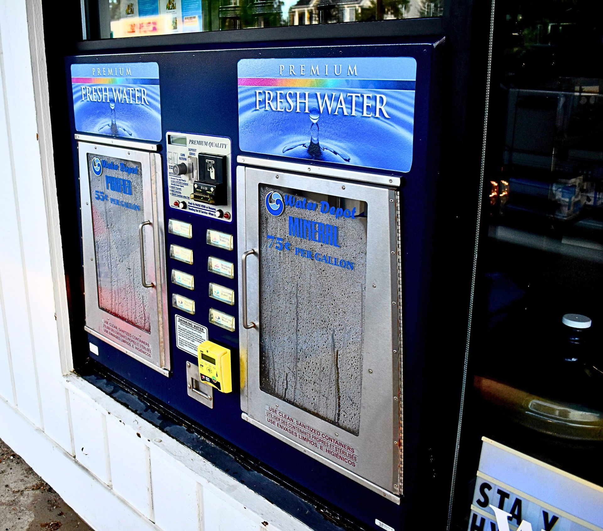 A dark blue water refill station in a shop window with text that reads, A dark blue water refill station in a shop window with text that reads,