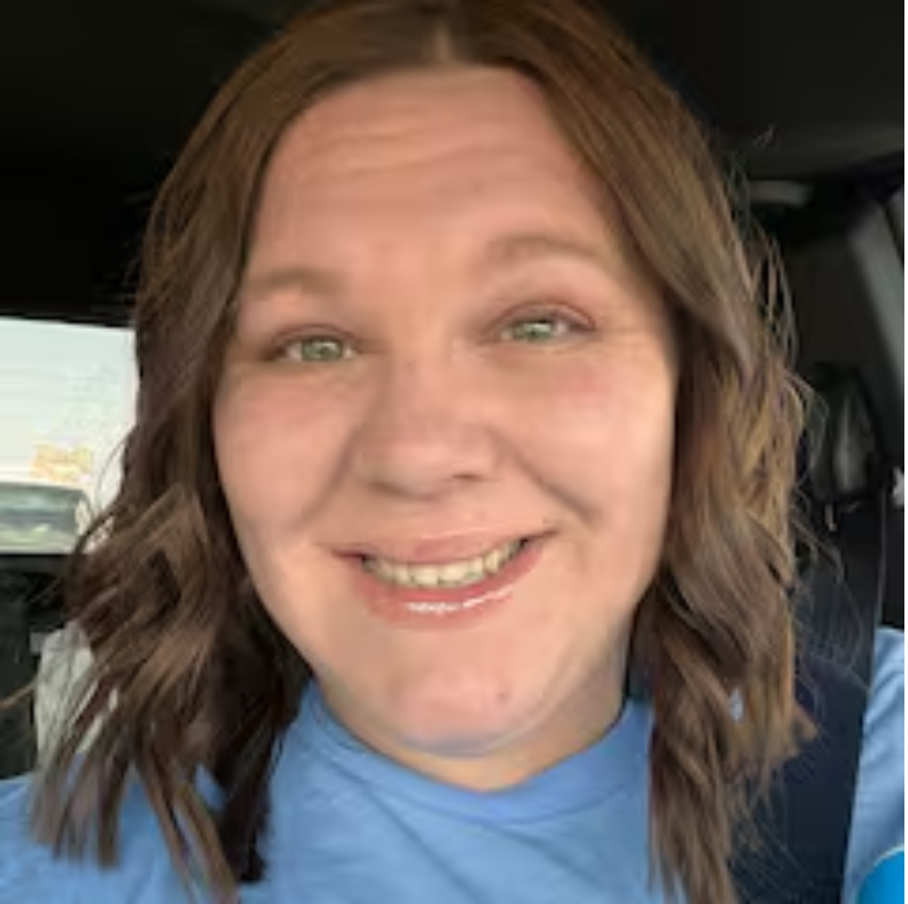 Man in red shirt and cap holding laughing child, woman kissing child's cheek.